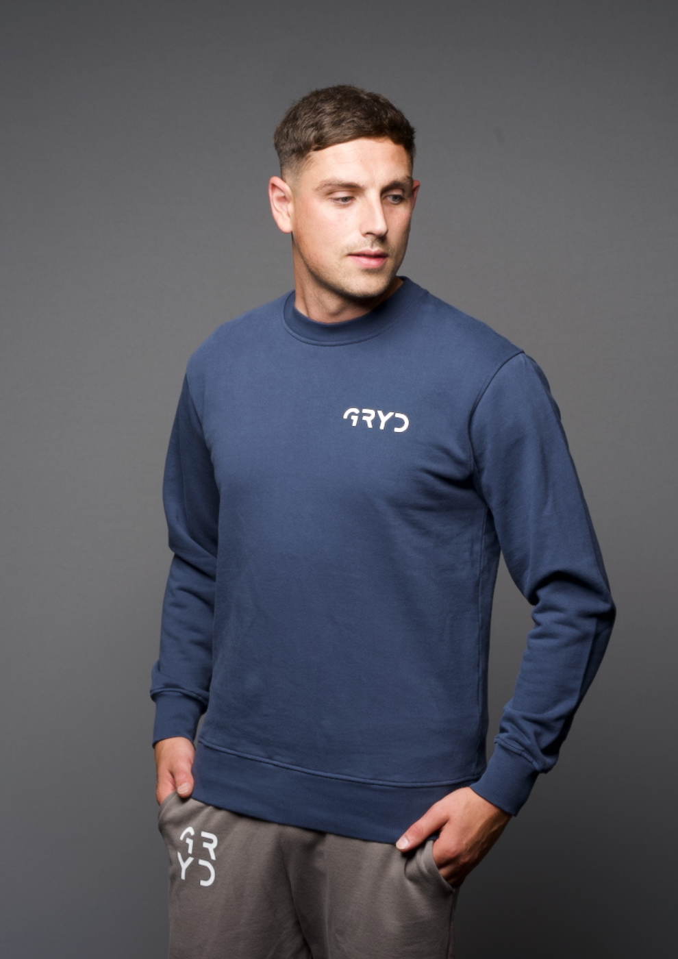 Man wearing a navy blue sweatshirt with 'GRYD' logo on a gray background